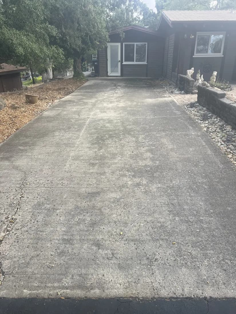 Residential driveway darkened with dirt and organic growth before pressure washing