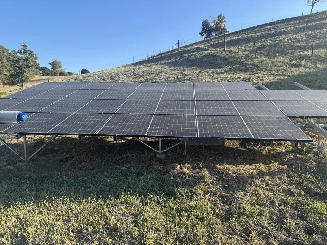 Ground mounted solar array coated in dust before cleaning, hillside behind