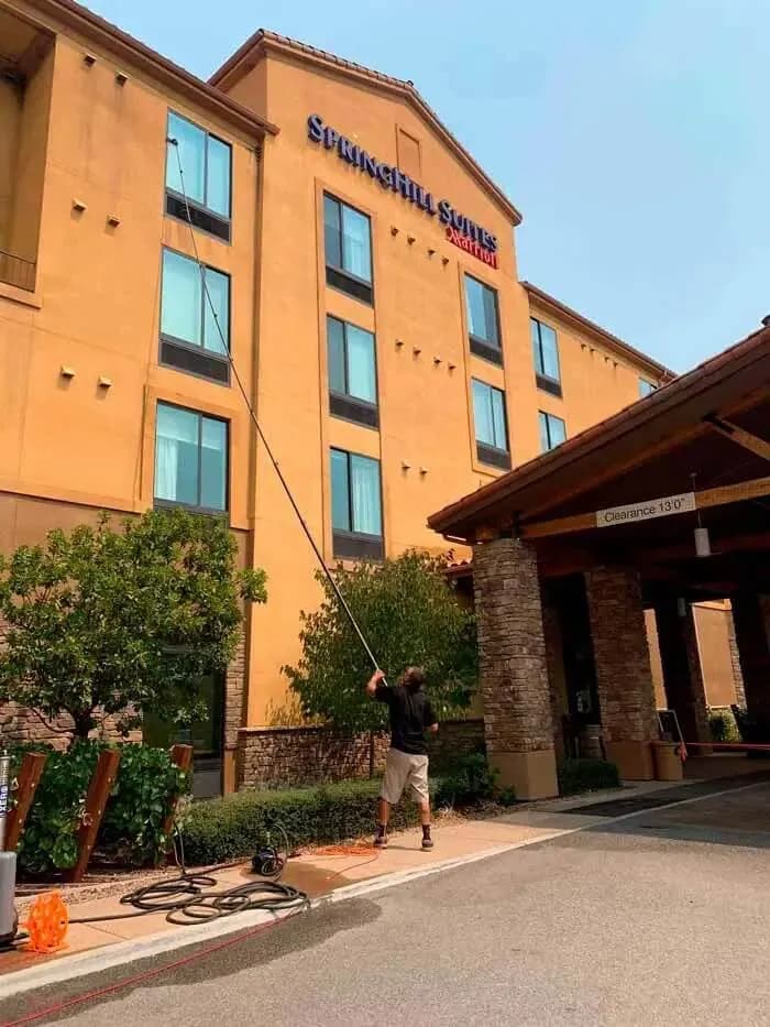 Exterior of a Central Coast hotel with a worker using a water fed pole at the entrance