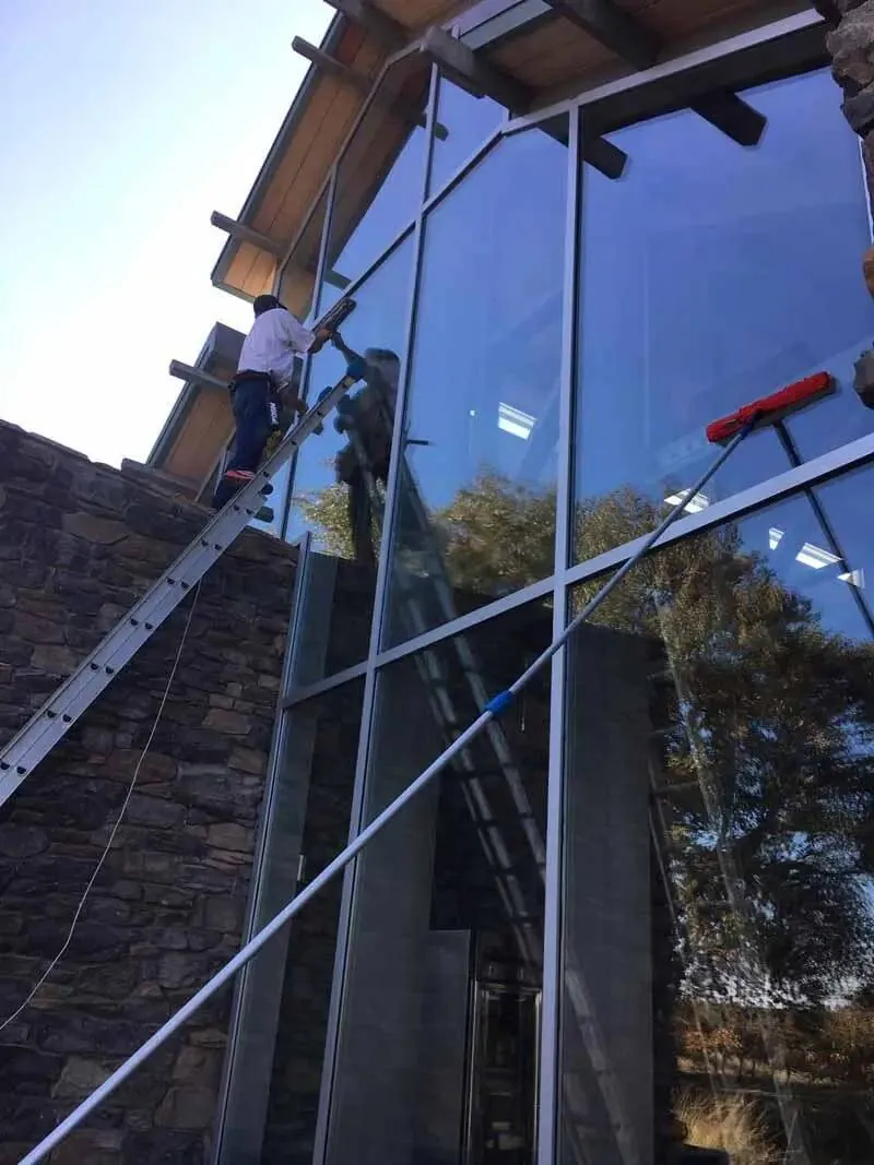 Close view of clean reflective glass on a building, showing sky and rooflines