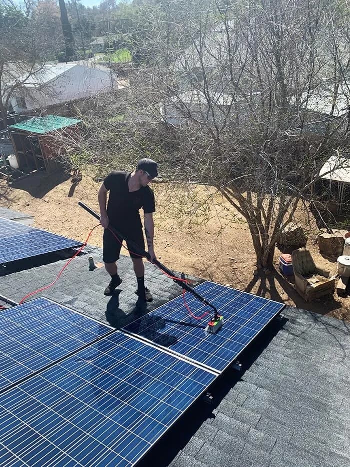 Cleaning roof mounted solar panels with a brush pole