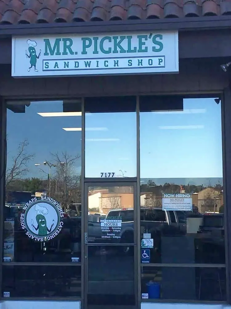 Clean storefront glass at a sandwich shop with cars reflected in the window