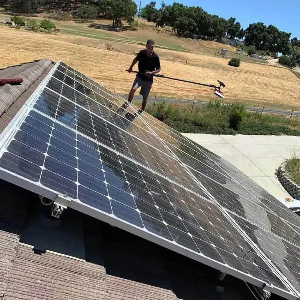 Cleaning a large ground mounted solar array with a brush pole in open country