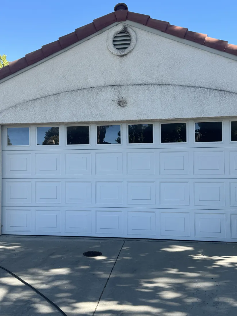 Stucco home with a clay tile roof and a clean white garage door