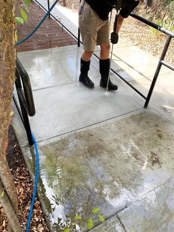 Pressure washing a concrete walkway with a wand